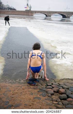 The woman-swimmer comes into ice water against the Troitsk bridge
