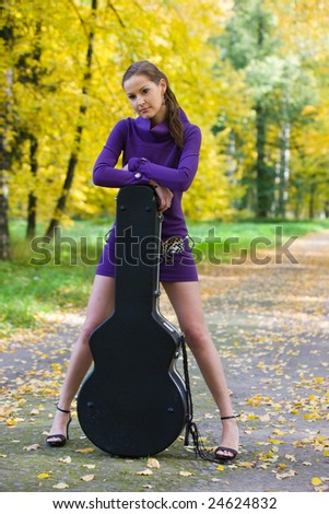 The beautiful girl with a guitar costs on a path in city park