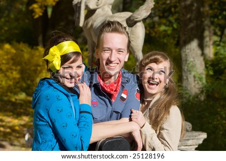 Two young women and the man laugh in park