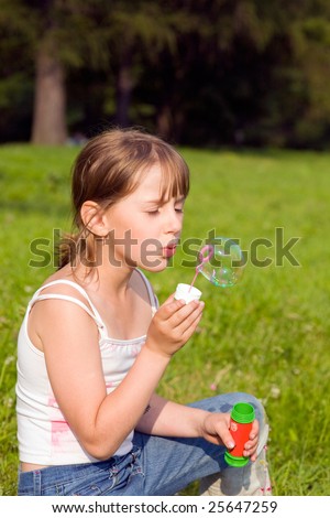 The girl and a soap bubble in sunny day