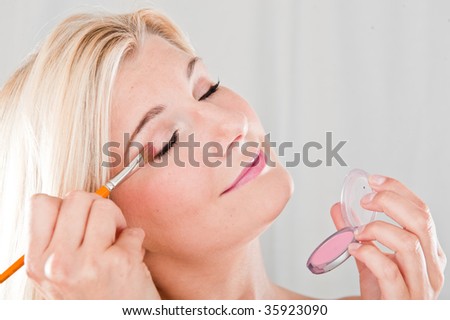 Close-up picture of a beautifull girl applying a eye make-up with a brush