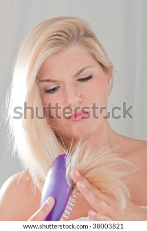 Picture of a young woman with long unhealthy hair and split ends having a problem to brush