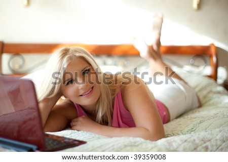 Pretty sexy girl working on laptop on the bed in her house