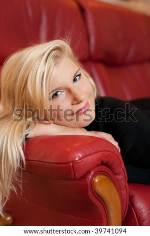 Young beautiful optimistic woman on red sofa