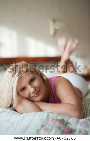 Young beautiful woman relaxing on the bed in her house