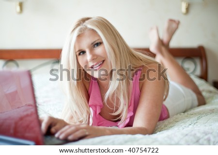 Young beautiful woman relaxing on sofa and chatting online on her laptop at home