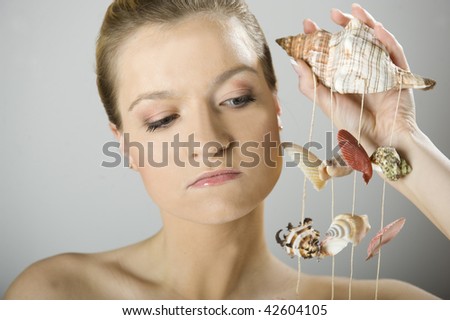 Young beautiful SPA woman with pure healthy skin holding sea shells