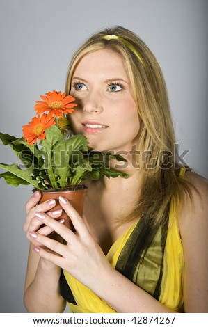 Young beautiful sexy woman in yellow dress smelling orange flower