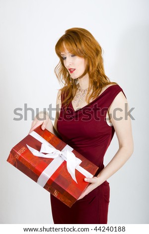 Glamour portrait of beautiful elegant sexy woman in red dress with red lips holding big red present ready for romantic celebration. gray background
