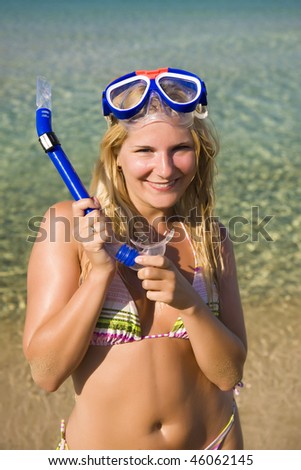 Young happy beautiful summer woman with swimming mask and snorkel preparing to dive in blue sea