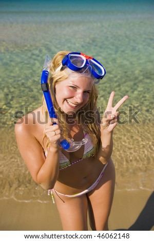 Young happy beautiful summer woman with swimming mask and snorkel preparing to dive in blue sea