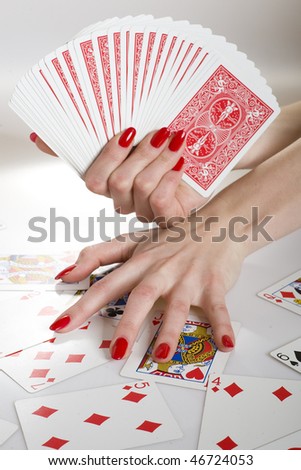 Beautiful hands with perfect red manicure holding a deck of playing cards
