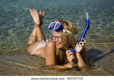 Young happy beautiful summer diving woman with swimming mask and snorkel preparing to dive in blue sea