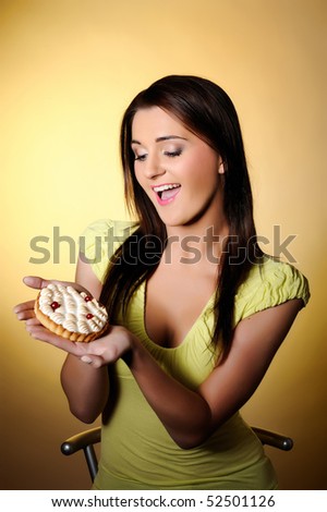 young beautiful girl eating small sweet cake. red background. copy-space. focus on the cake