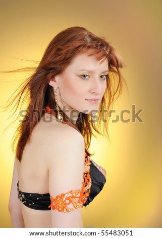 Beautiful mystic woman with golden make-up in belly dance costume. yellow background