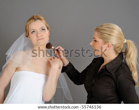 Natural Wedding make-up is being applied to pretty bride. gray background