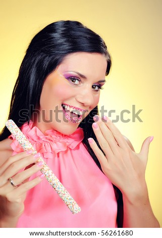Beautiful happy girl with a sweet lollipop and creative makeup . yellow background
