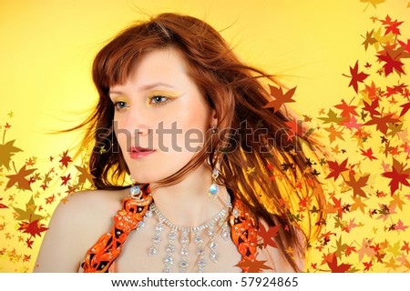 Beautiful autumn fairy woman with golden make-up and hair of falling leaves.
