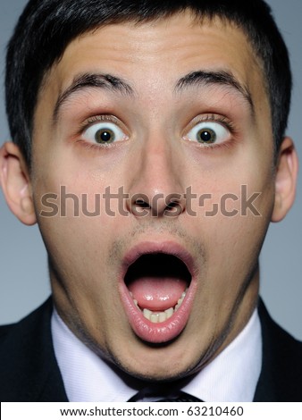 Portrait of funny surprised business man in formal suit and black tie . expressions on gray background