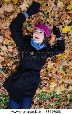 Pretty autumn girl relaxing outdoors in the forest on the fallen leafs