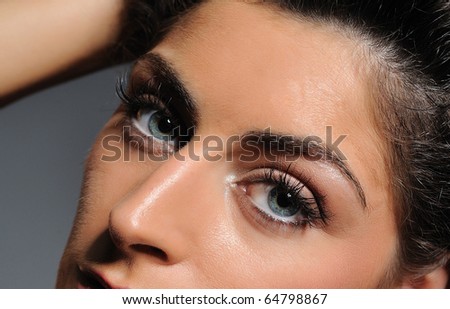Beautiful macro shot of blue eyes with long lashes and make-up in brown tones
