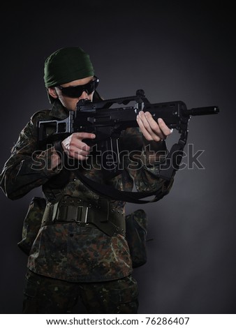 Young soldier in camouflage and ammunition with a gun. studio shot