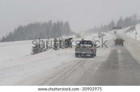 Slippery winter highway causes a vehicle to lose control and flip onto it\'s side in the highway median