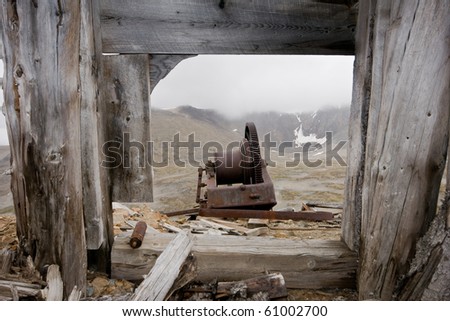 An old gear wheel is framed though wooden beams at an old mine site in Yukon Territory