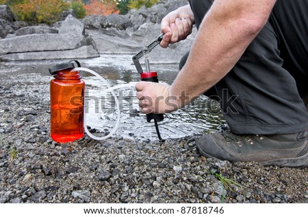 A person uses a lightweight compact water filter to pump safe drinking water