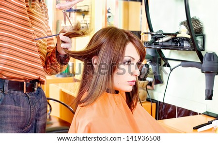 pretty woman and hands of hairdresser in hair salon, cutting hair