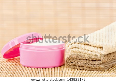 Hand cream in pink cup with two towels