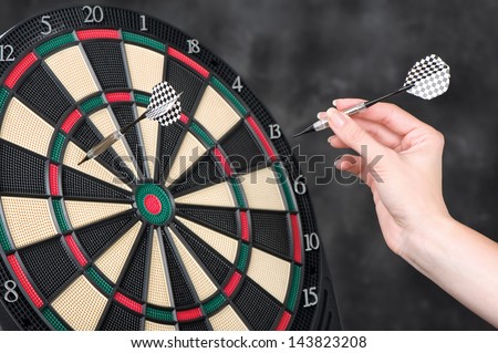 Female hand throwing darts at dartboard