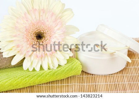 Ready to use skin care product, fresh flower on top of two towels and skin care product