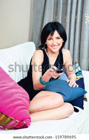 Happy woman on bed with remote controller in hand