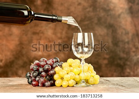 pour wine from bottle in shiny wine cup near grape