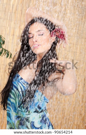 young woman with orchid in her hair enjoying under shower