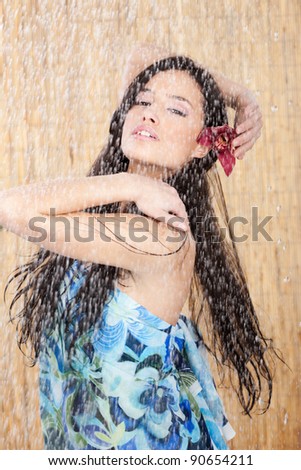 Sensual woman with orchid in her hair having a shower