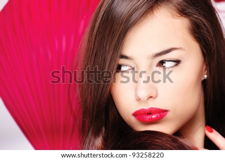 Pretty lady with big red lips in front of a red fan