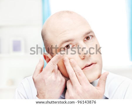 Close up of a man putting contact lens in his eye at home
