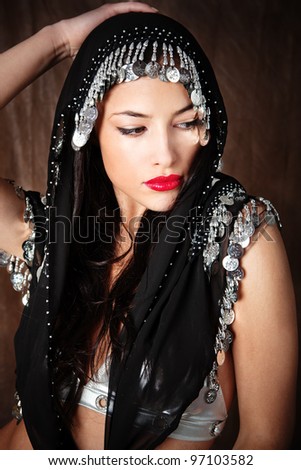 beautiful young woman covered with black scarf holding hand on her head
