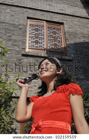 chinese beauty with sunglasses behind an old house.