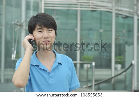 Young happy asian businessman calling on mobile phone, outdoor, smiling.