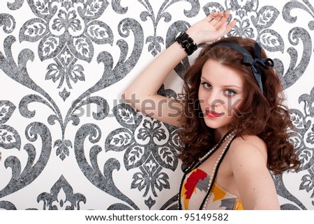 Young beautiful woman in retro dress on vintage wallpaper background
