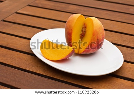 Fresh juicy peach on oval plate on wooden background