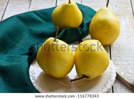 Set of fresh pears on plate on wooden table. Selective focus.