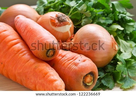 Fresh raw carrots, onion and parsley on wooden table. Selective focus