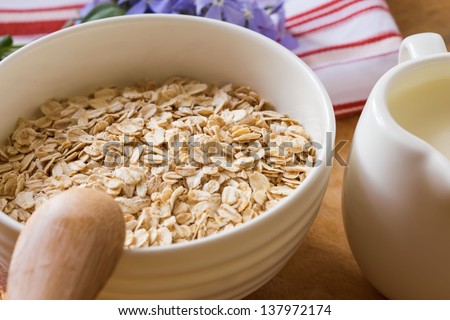 Oat flakes in orange bowl  on wooden table. Selective focus.