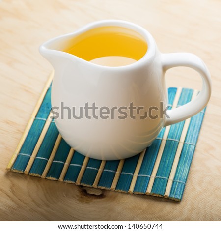 Sunflower/olive oil in pitcher on wooden background. Selective focus.