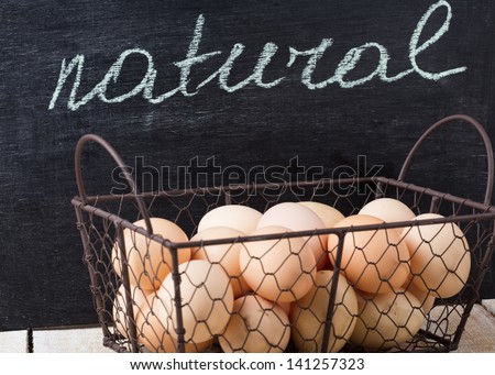 Fresh organic eggs in bucket on wooden background. Rustic style. Blackboard with word natural. Organic/natural/bio products. Selective focus.
