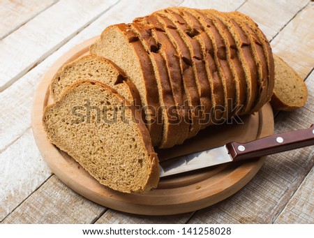 Sliced loaf of bread on board on wooden background